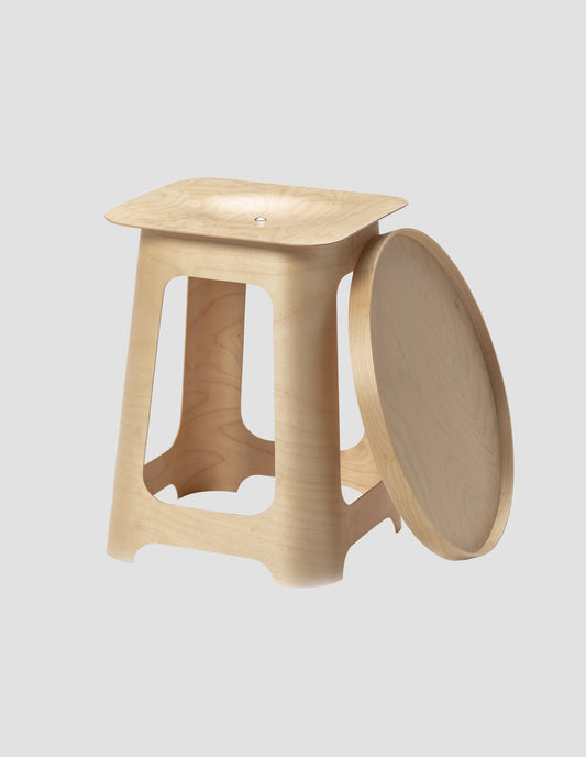 The Isokon stool with the round tray next to it on the floor, leaning against it.