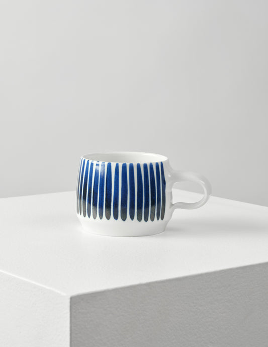 Front view of white porcelain cup with hand painted blue vertical stripes.