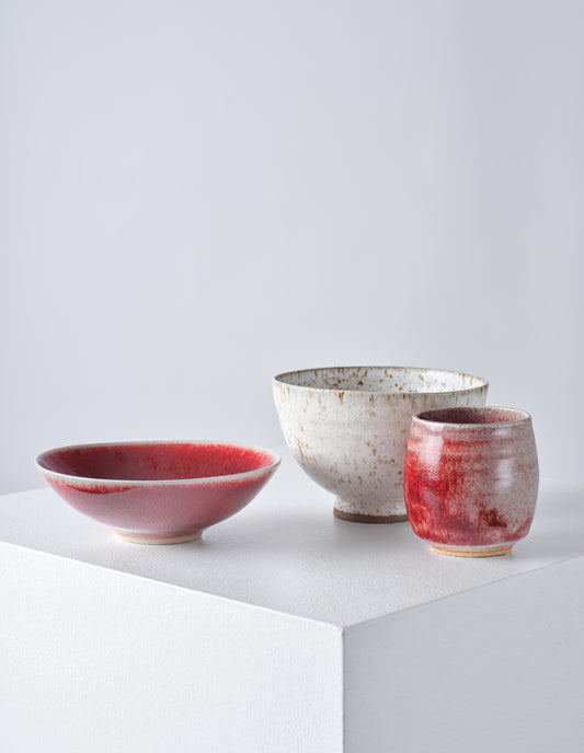 Group shot of Keiko Hasegawa's work including the dark read stoneware bowl, natural high foot speckled bowl and dark red beaker.