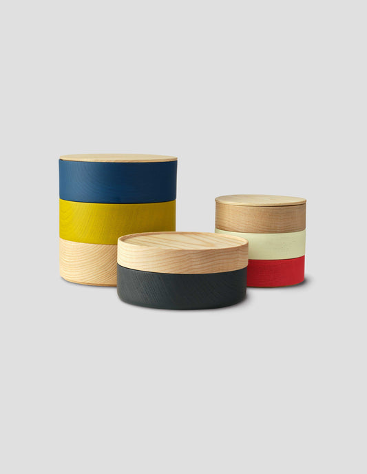 A group shot of three round wooden storage boxes with colourful painted bands.