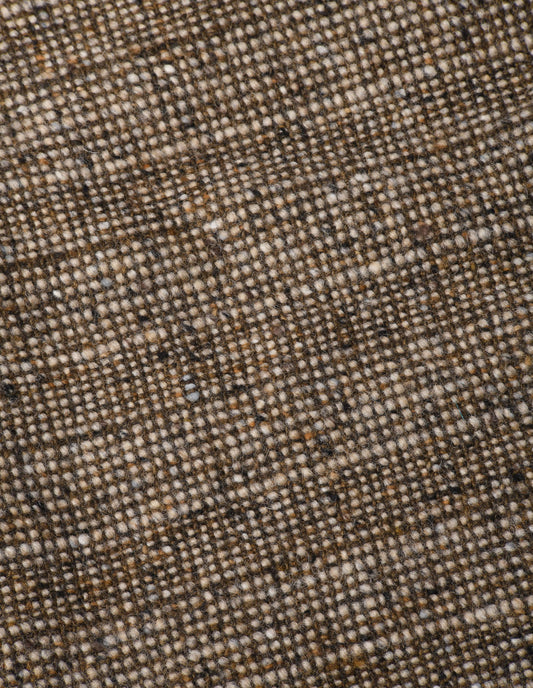 A close up view showing in detail the woven pattern created by the oatmeal base interwoven with an earthy brown yarn with flecks of warm browns and greys.