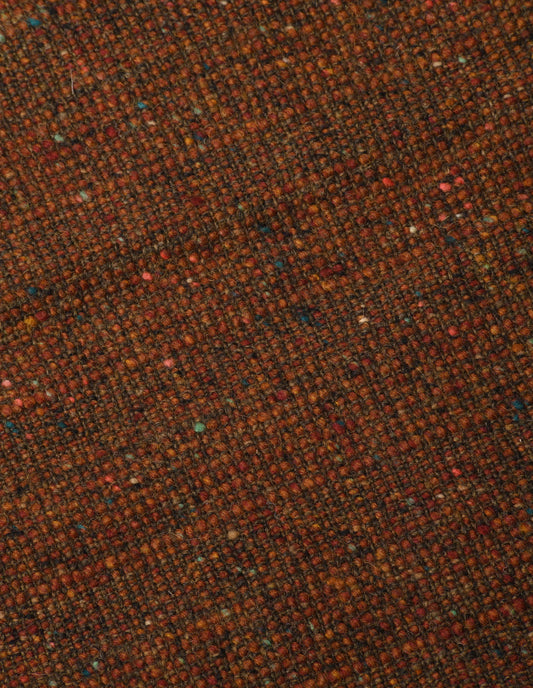 A close up view showing in detail the woven pattern created by the vibrant orange rust yarn, interwoven with flecks of warm autumnal oranges and earthy browns.