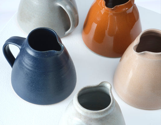 Top view of Nicola Tassie's small glazed stoneware jugs in a selection of colours.