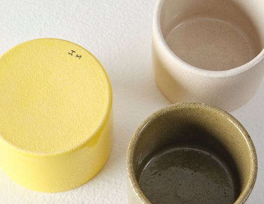 A group of three Ian Mcintyre round pots viewed from above showing the bottom of one with the initials IM.