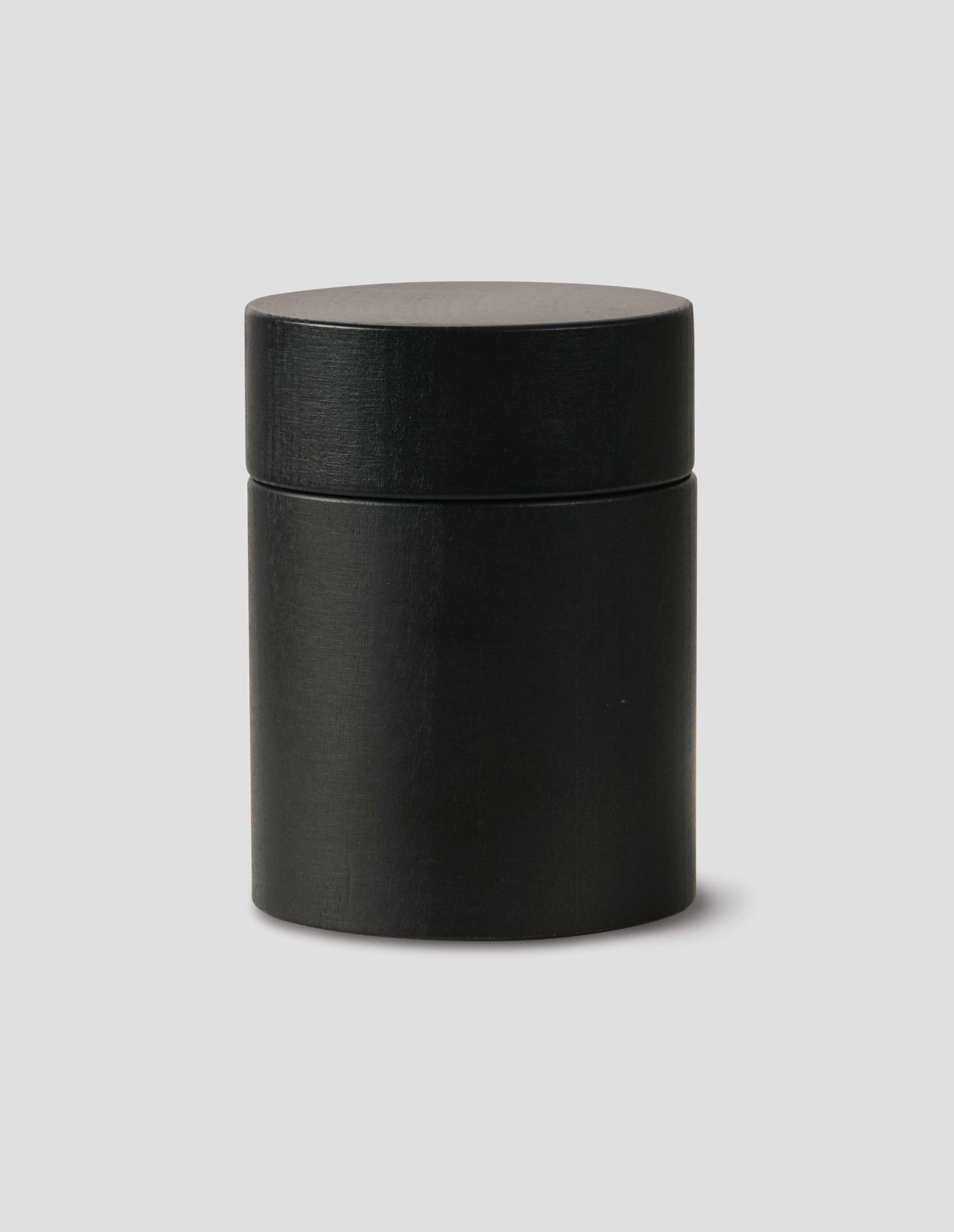 A front flay lay view of a matte black cylindrical salt and pepper mill.
