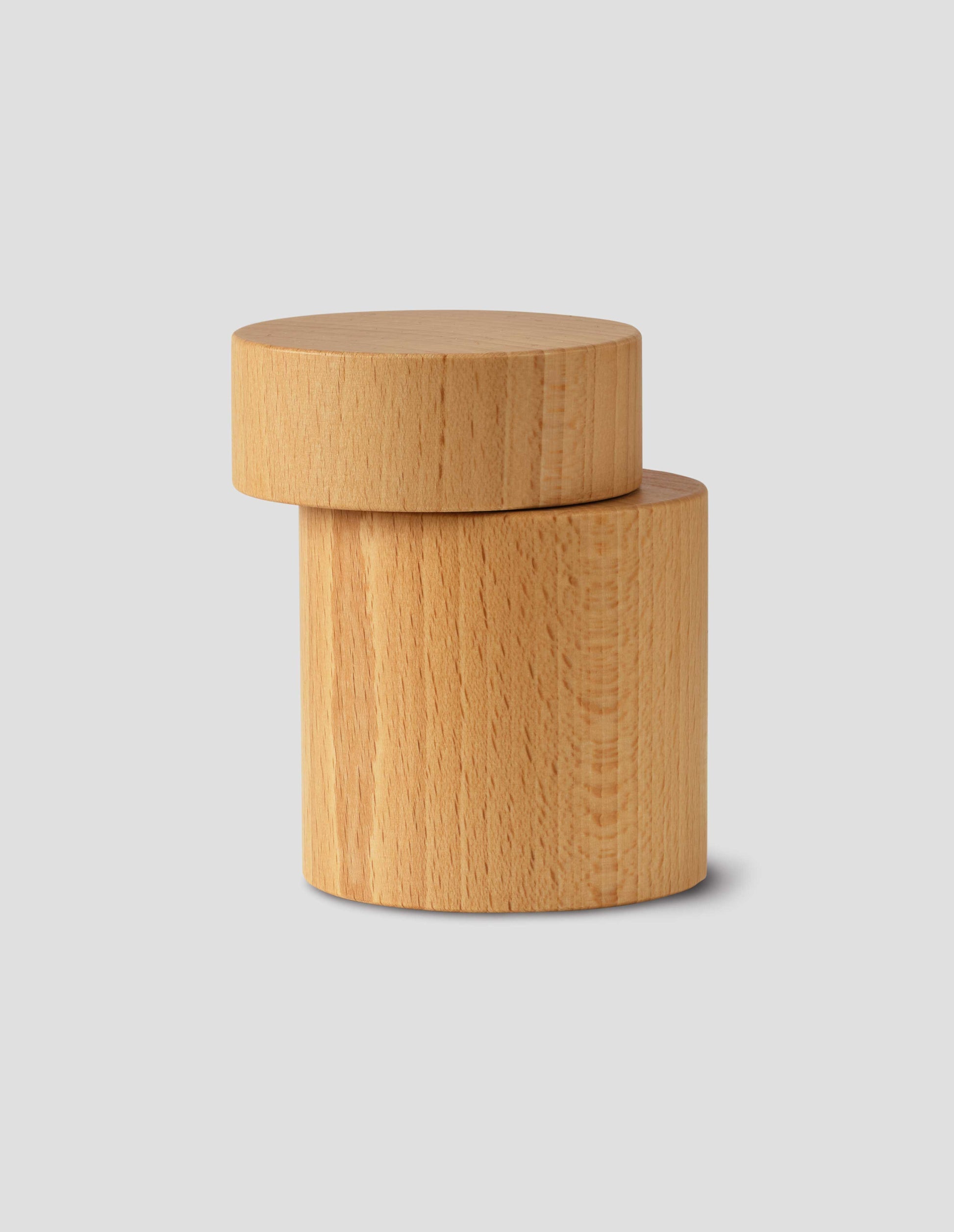 A front flay lay view of a wooden cylindrical salt and pepper mill, showing the grinding functionality. 
