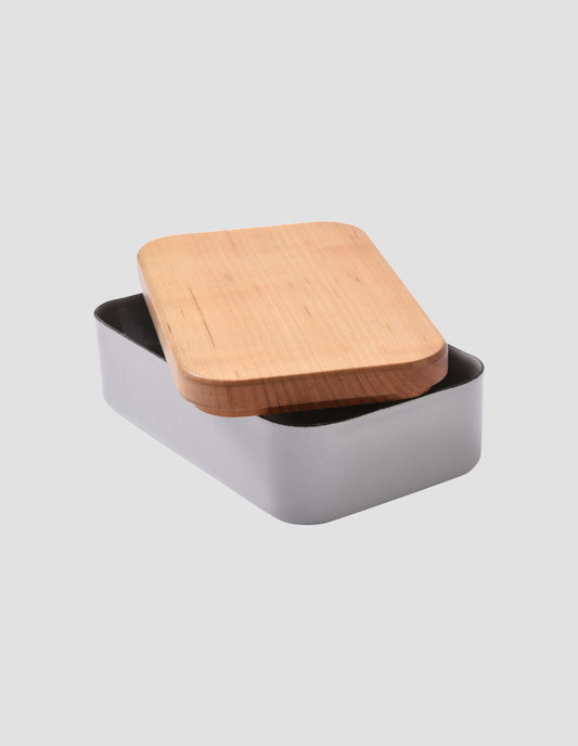 The cherry wood lid removed and placed at an angle on top of the small grey enamel butter dish.