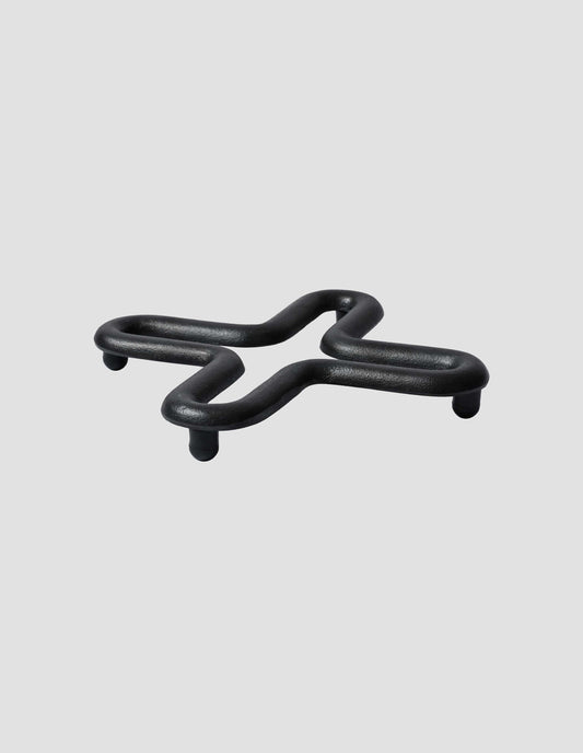 A side view of the back cast iron square trivet showing its small feet to keep your kettle or teapot elevated from the surface.