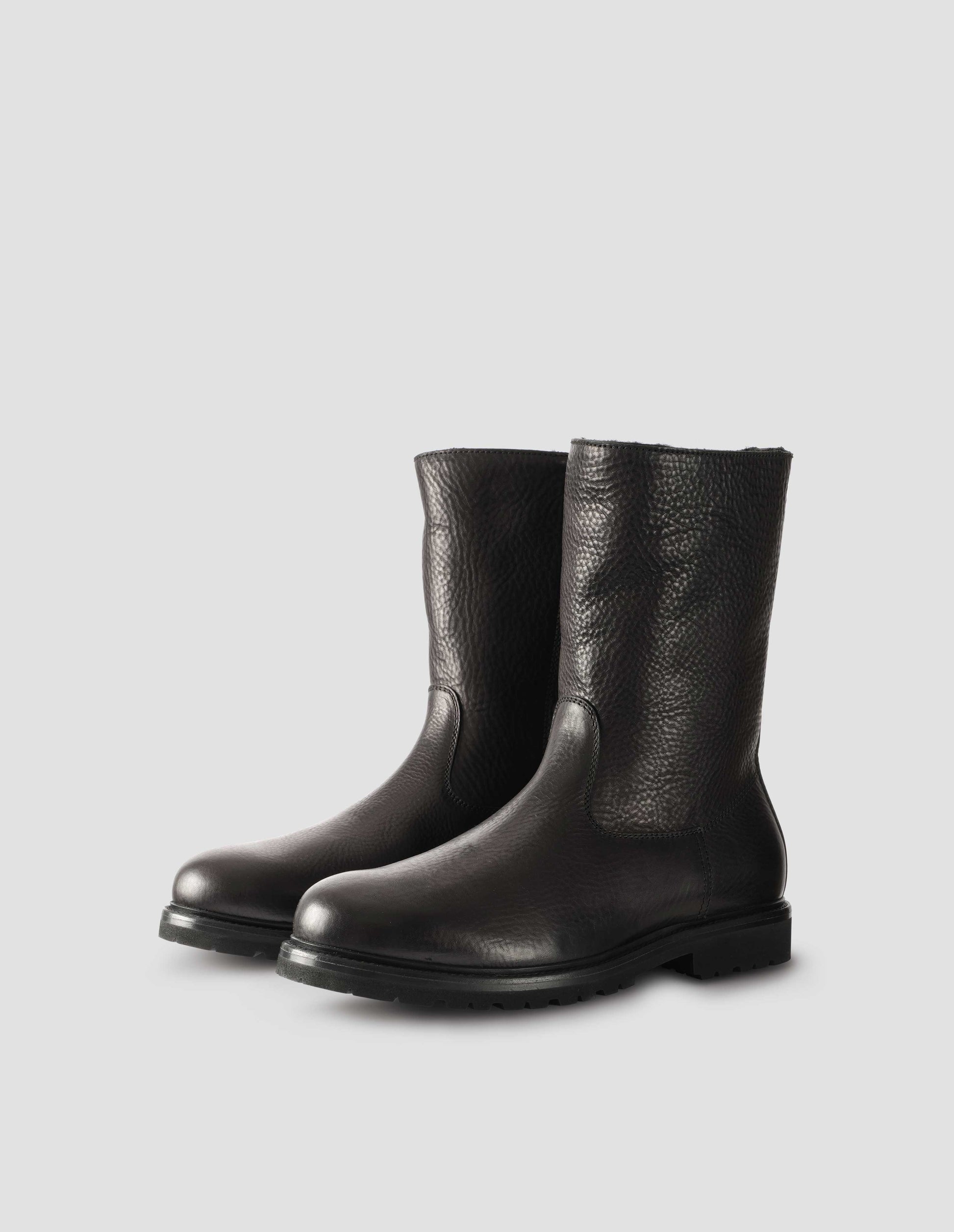 Black leather three quarter length boots with Vibram sole and shearling lining. Side view flat lay.