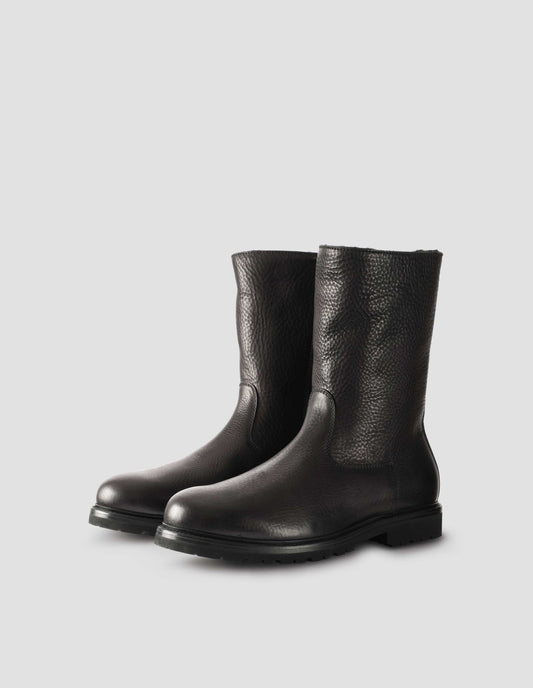 Black leather three quarter length boots with Vibram sole and shearling lining. Side view flat lay.