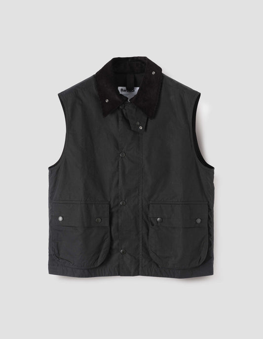 Black gilet with storm tab on corduroy collar, press stud fastening storm flap, large bellows pockets with press stud fastening envelope closure. Front flat lay view.