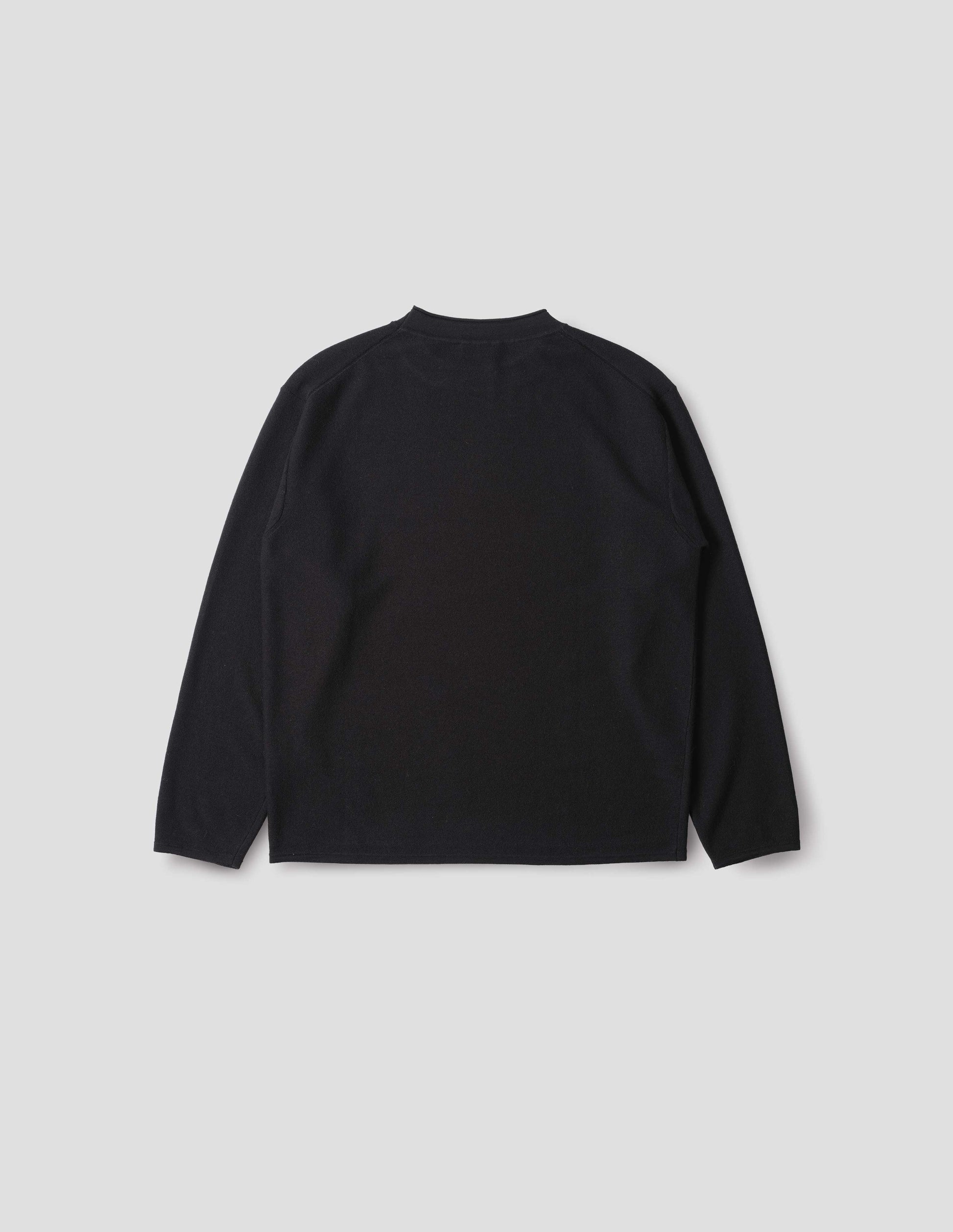 Black crew neck jumper with rolled edge detailing on neck, rib trim on cuffs and hem. Back flat lay view.