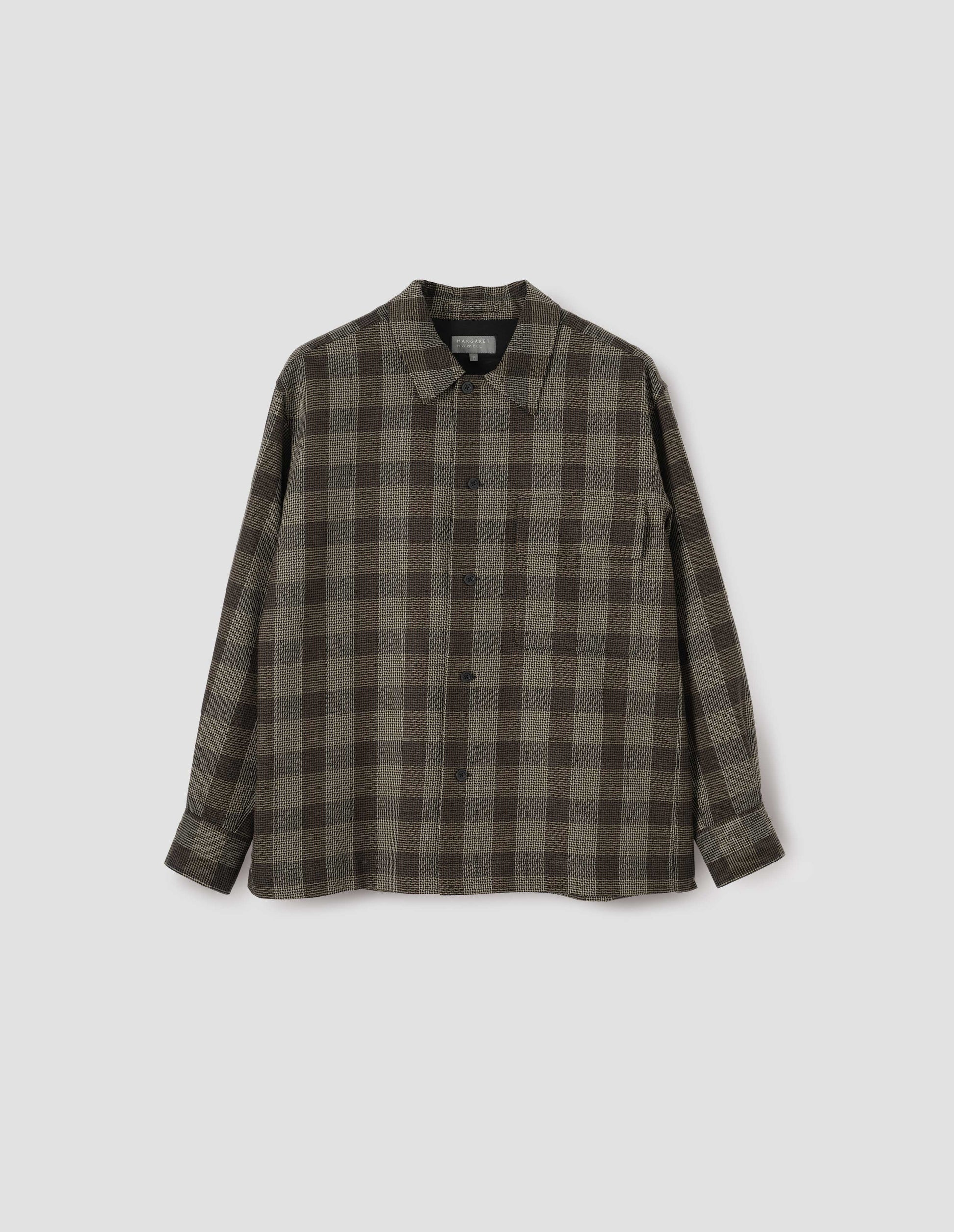 Black, brown and green checked wool shirt, with horn button fastening, deep placket and flap patch pocket. Front flat lay view.