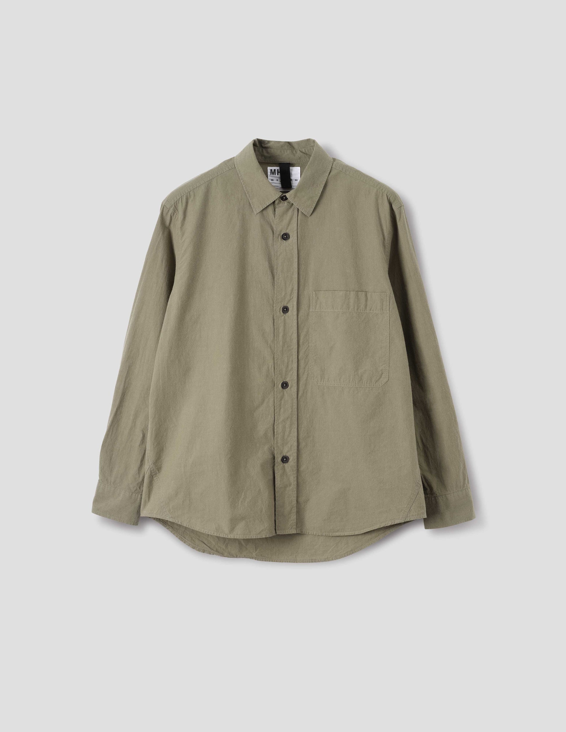 Green brushed cotton shirt with raised placket, large chest pocket, corozo button closure and side gusset stitch detailing. Front flat lay view.