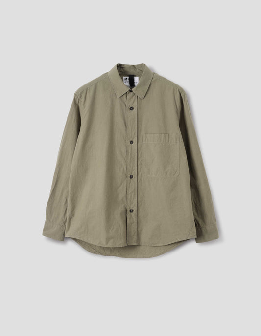 Green brushed cotton shirt with raised placket, large chest pocket, corozo button closure and side gusset stitch detailing. Front flat lay view.