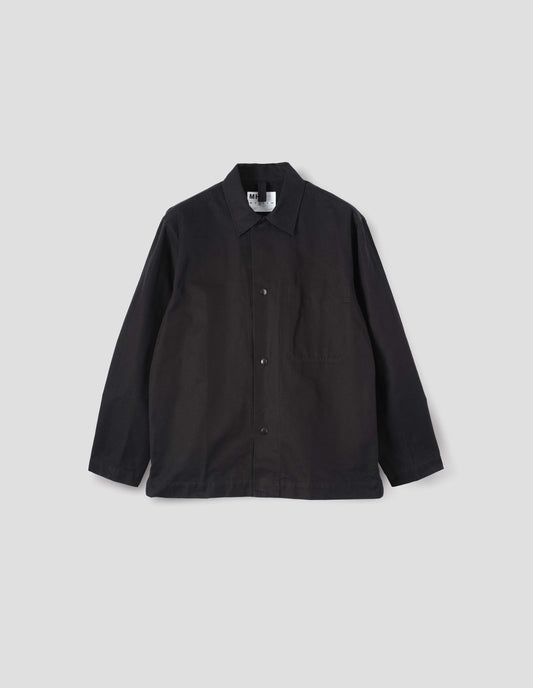 Black overshirt with press stud fastenings, stitch through chest pocket and adjustable cuffs. Front flat lay view.