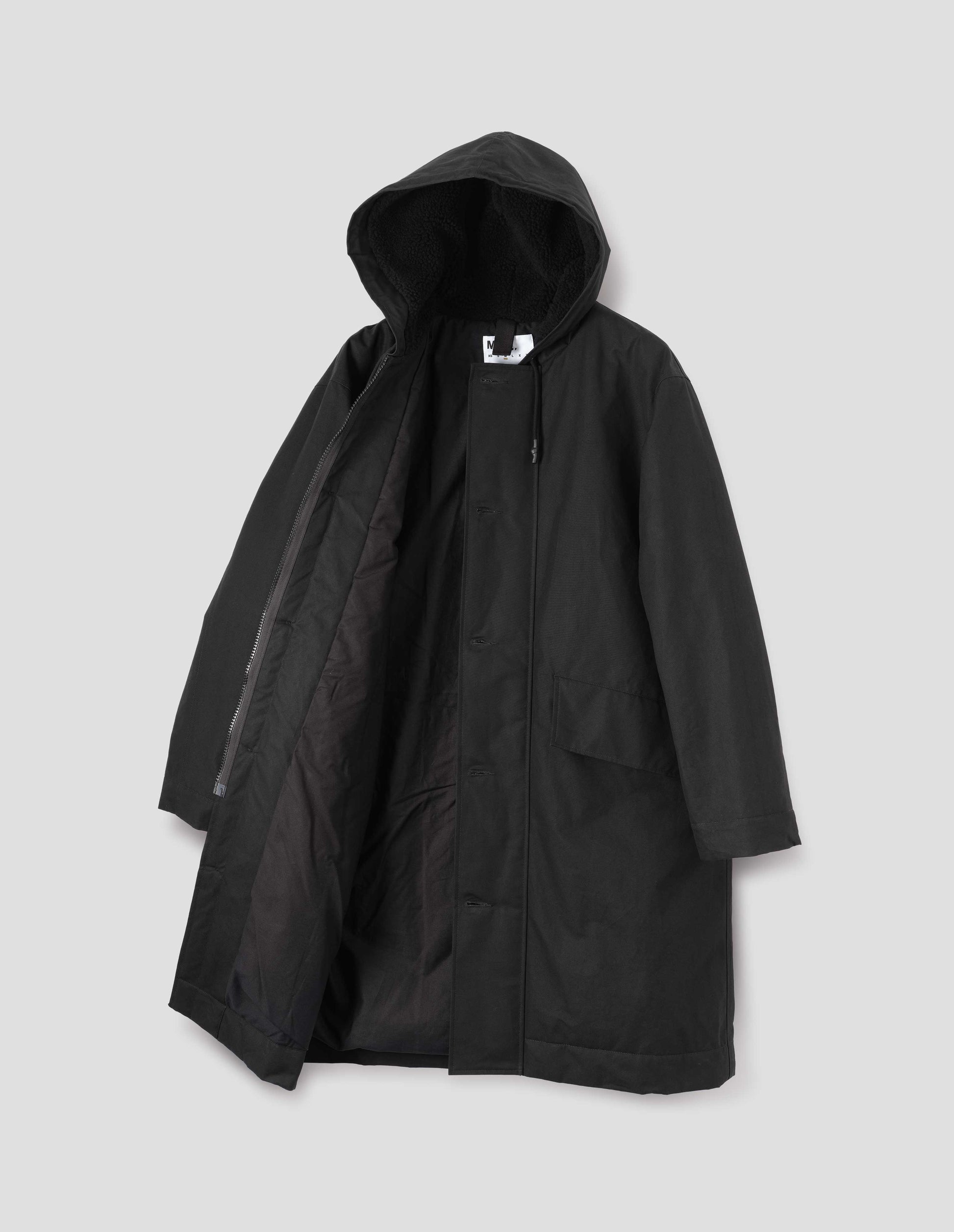 Black hooded parka with fleece lined drawcord hood, two way zip fastening with button fastening storm flap and slanted flap pockets. Front flat lay open view.