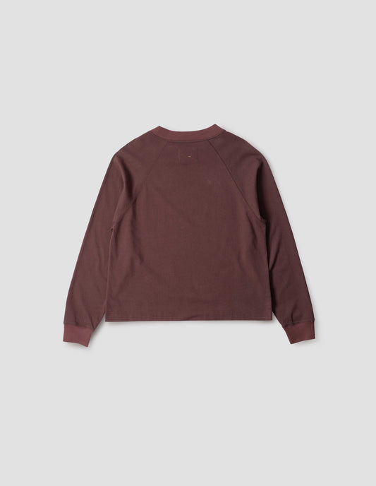 Reddish purple long sleeve t-shirt with raglan sleeve, single rib trims on neck and cuffs and vent split hem. Back flat lay view.