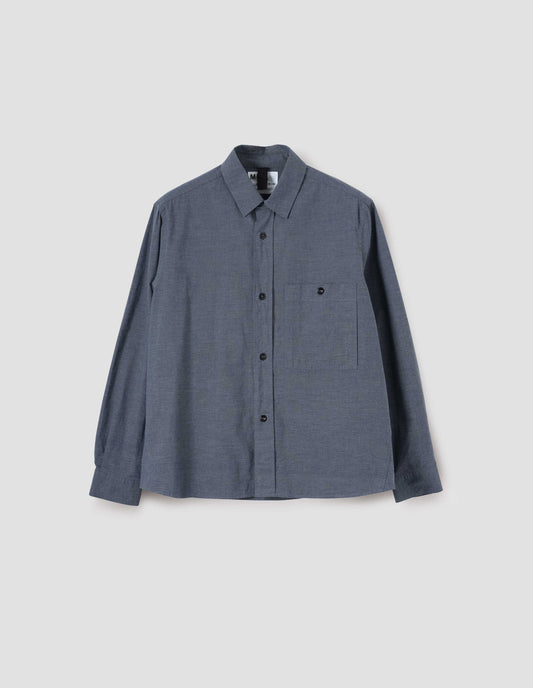 Blue long sleeve shirt, with raised placket, corozo button closure and chest patch pocket, front flat lay view.