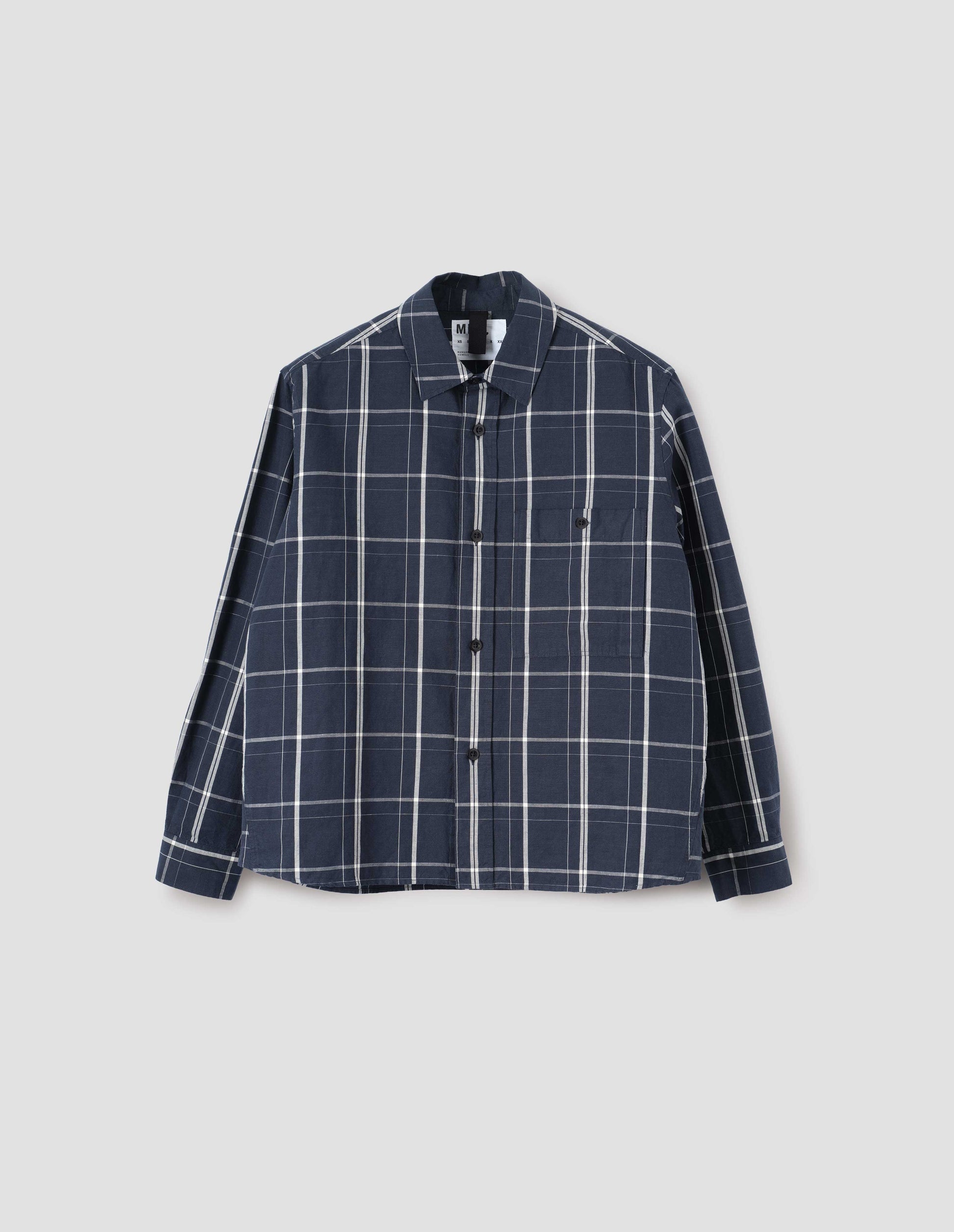 Blue and white checked long sleeve shirt. With raised placket, corozo brace buttons and button through chest patch pocket. Front flat lay view.