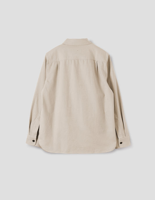 Beige overhead shirt with corozo button closure cuffs and elongated back hem. Back flat lay view.