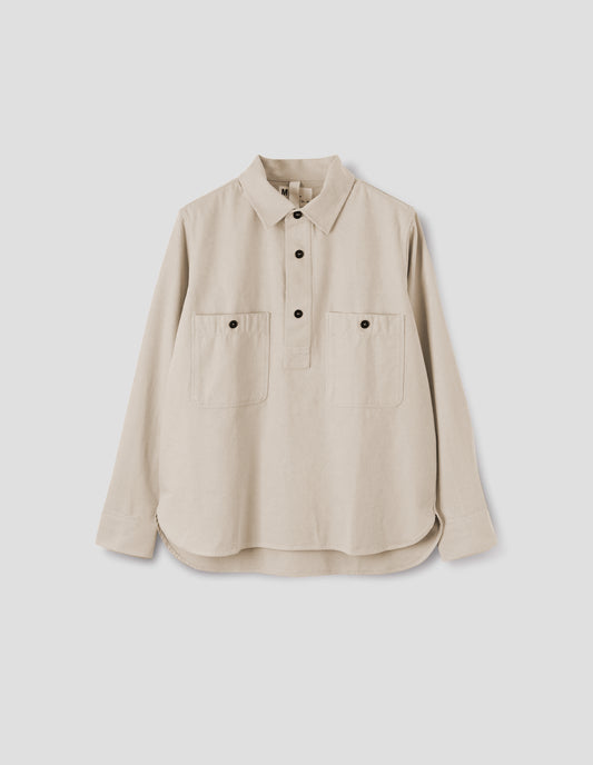 Beige overhead shirt with raised placket, box stitch detailing, button through chest patch pockets and elongated back hem. Front flat lay view.