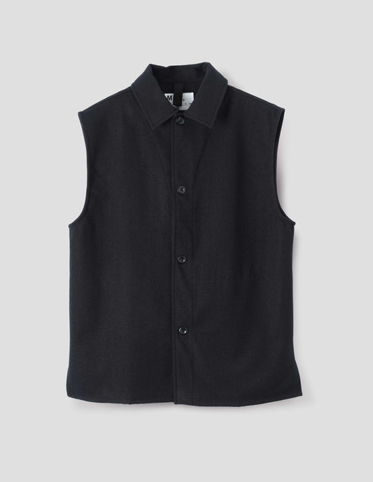 Black sleeveless wool cotton drill overshirt with stitch through facing, vent split hem and stitch through internal pocket. Front flat lay view.