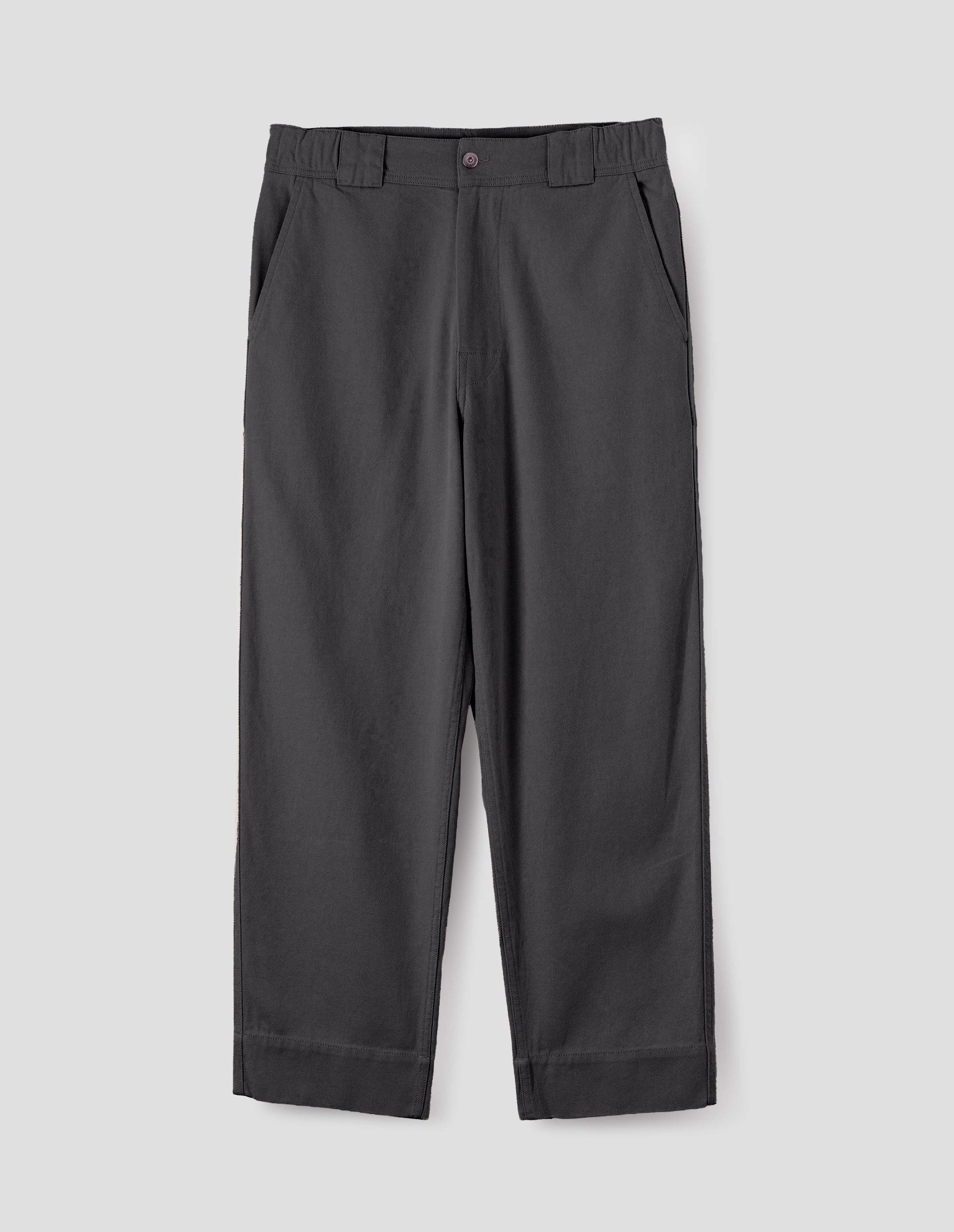 Grey trousers with button fastening, side elasticated waistband, wide belt loops and deep hem. Front flat lay view. 
