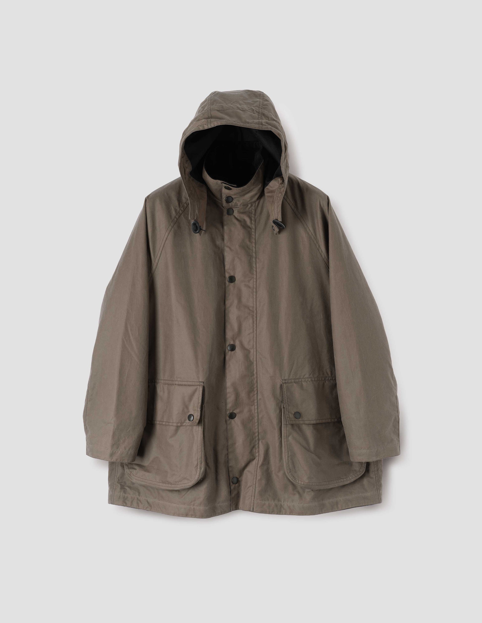 Dark beige parka with stand collar and hood with wire adjustable peak, raglan sleeve, press stud fastening storm flap and large bellows pockets with press stud fastening envelope closure. Front flat lay view.