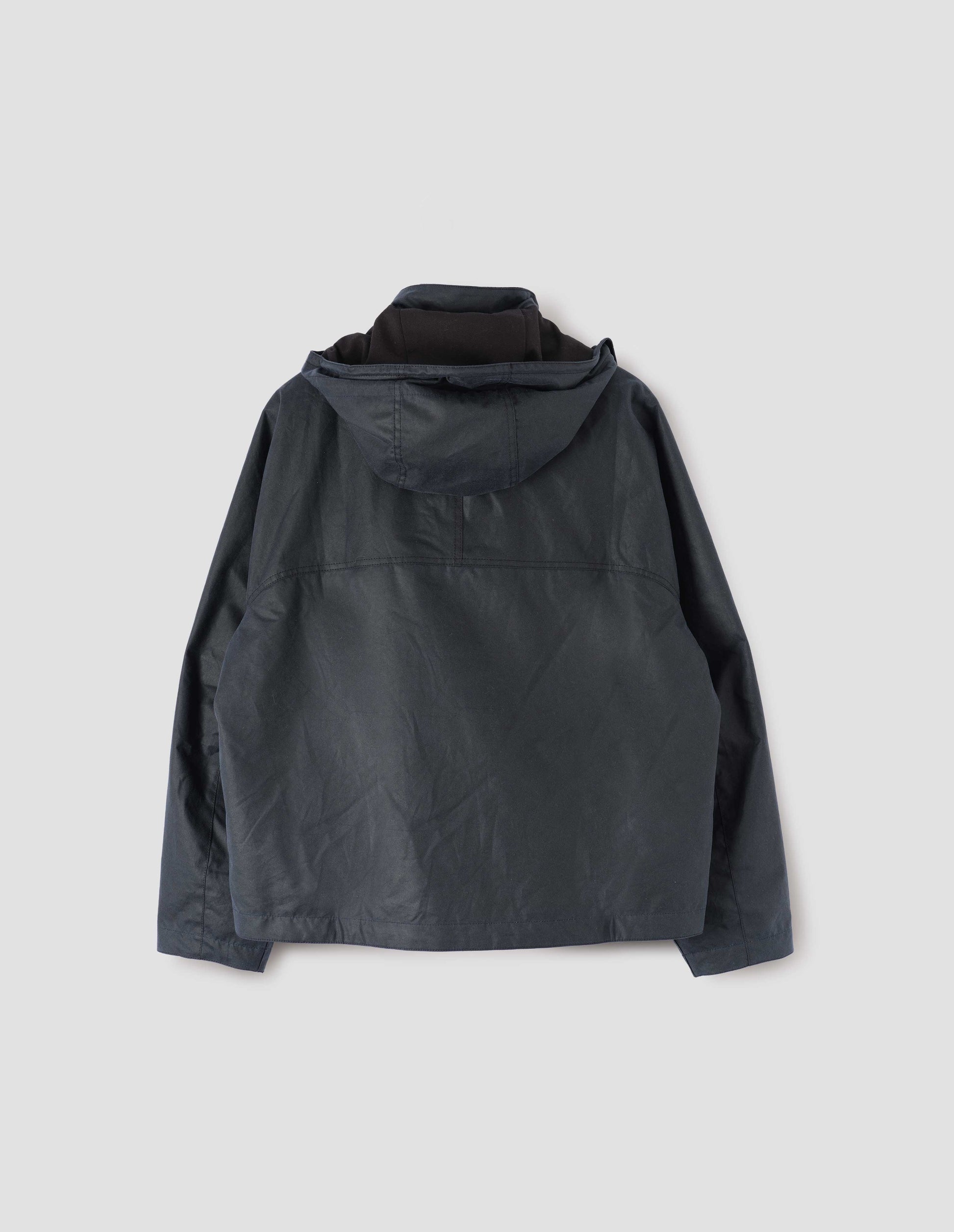 Dark blue boxy jacket with stand collar, hood and raglan sleeve. Back flat lay view.