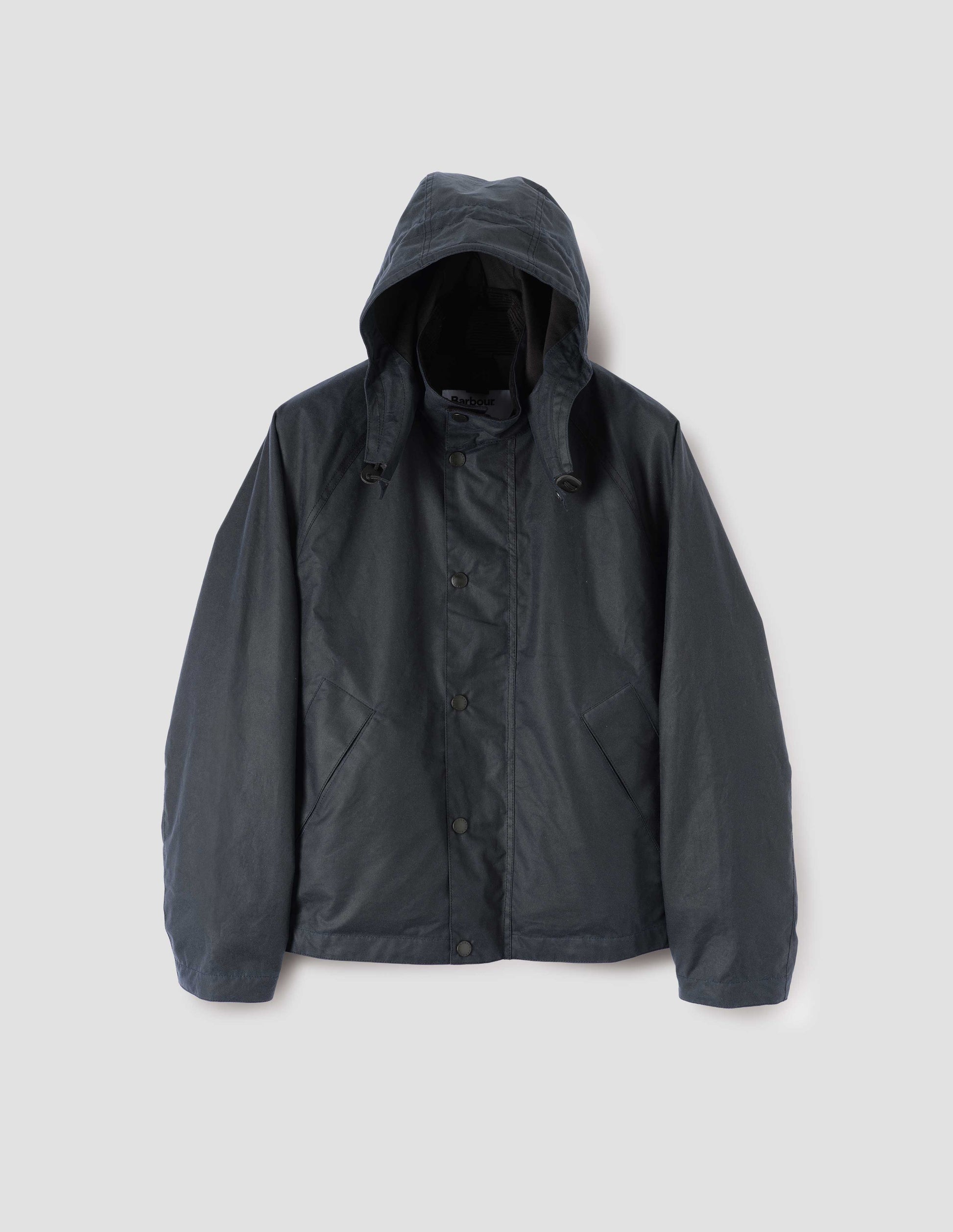 Dark blue boxy jacket with stand collar and hood with wire adjustable peak, raglan sleeve, press stud storm flap and wide storm welt side pockets. Front flat lay view.