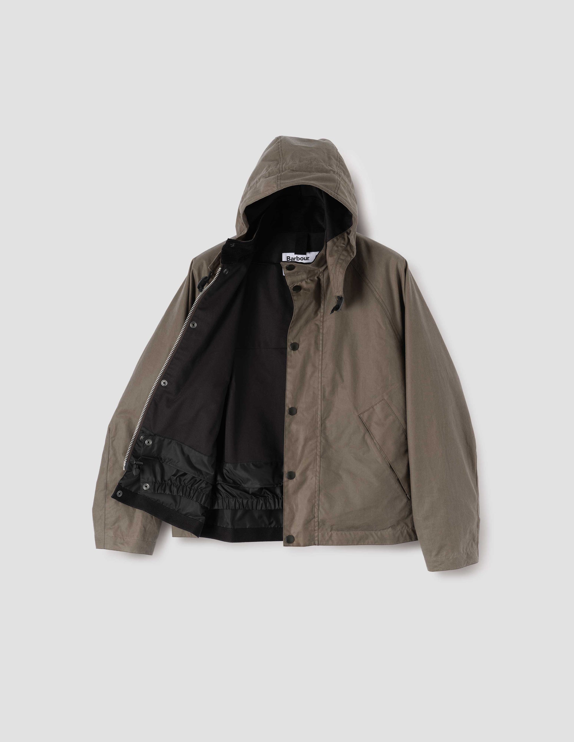Dark beige cotton drill lined boxy jacket with stand collar and hood with wire adjustable peak, raglan sleeve, two-way zip fastening, press stud storm flap, wide storm welt side pockets and elasticated snow skirt inside. Open flat lay view.