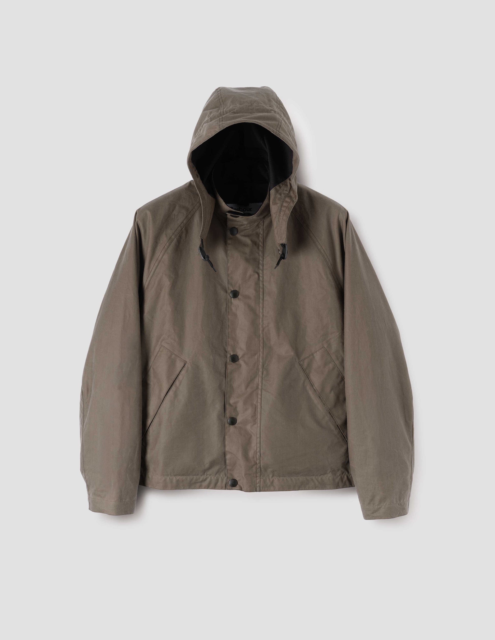 Dark beige cotton drill lined boxy jacket with stand collar and hood with wire adjustable peak, raglan sleeve, press stud storm flap and wide storm welt side pockets. Front flat lay view.