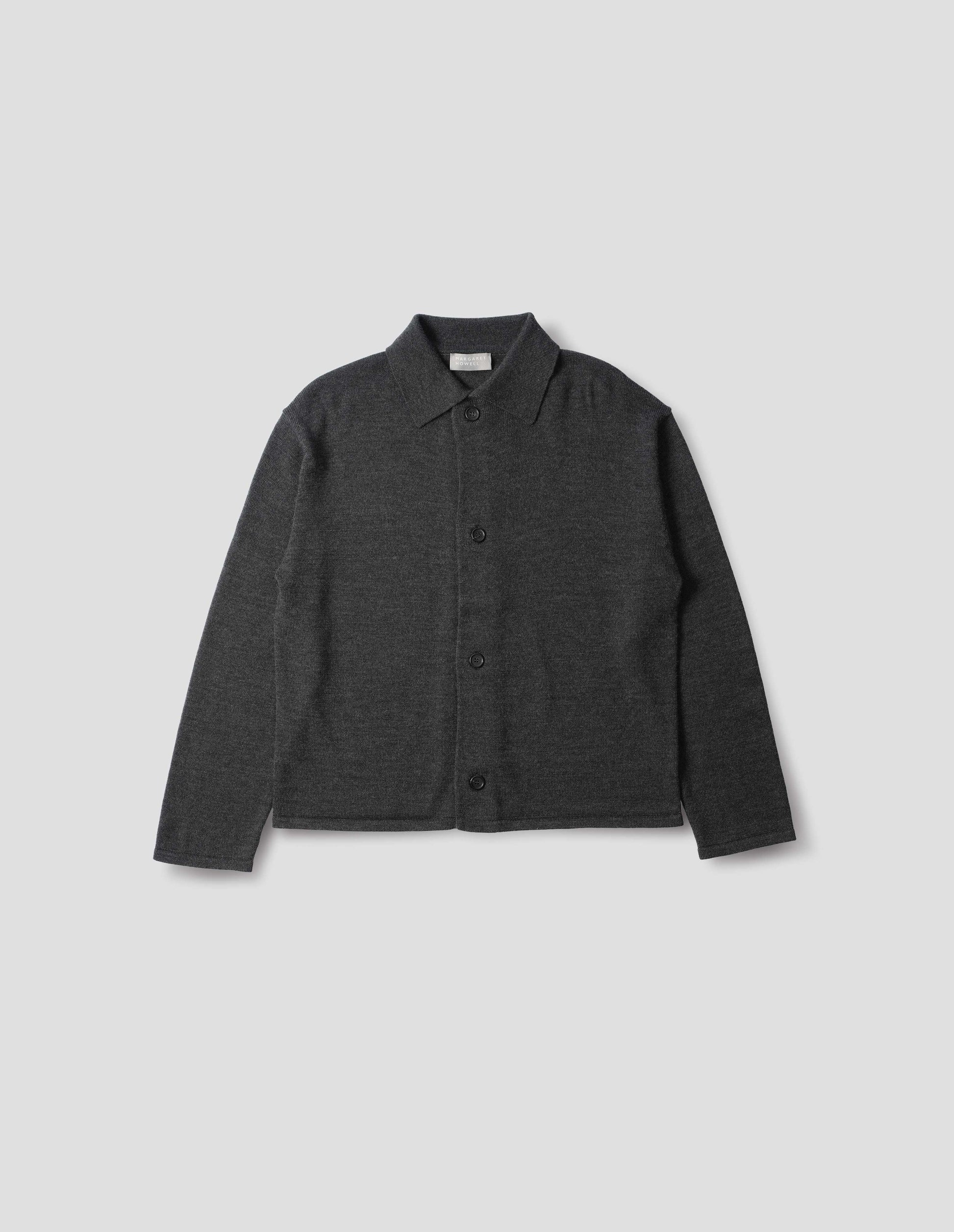 Dark grey merino cardigan with jersey stitch, fully fashioned collar, horn button fastening, set-in fully fashioned sleeves, and tubular hem and cuffs. Front flat lay view.