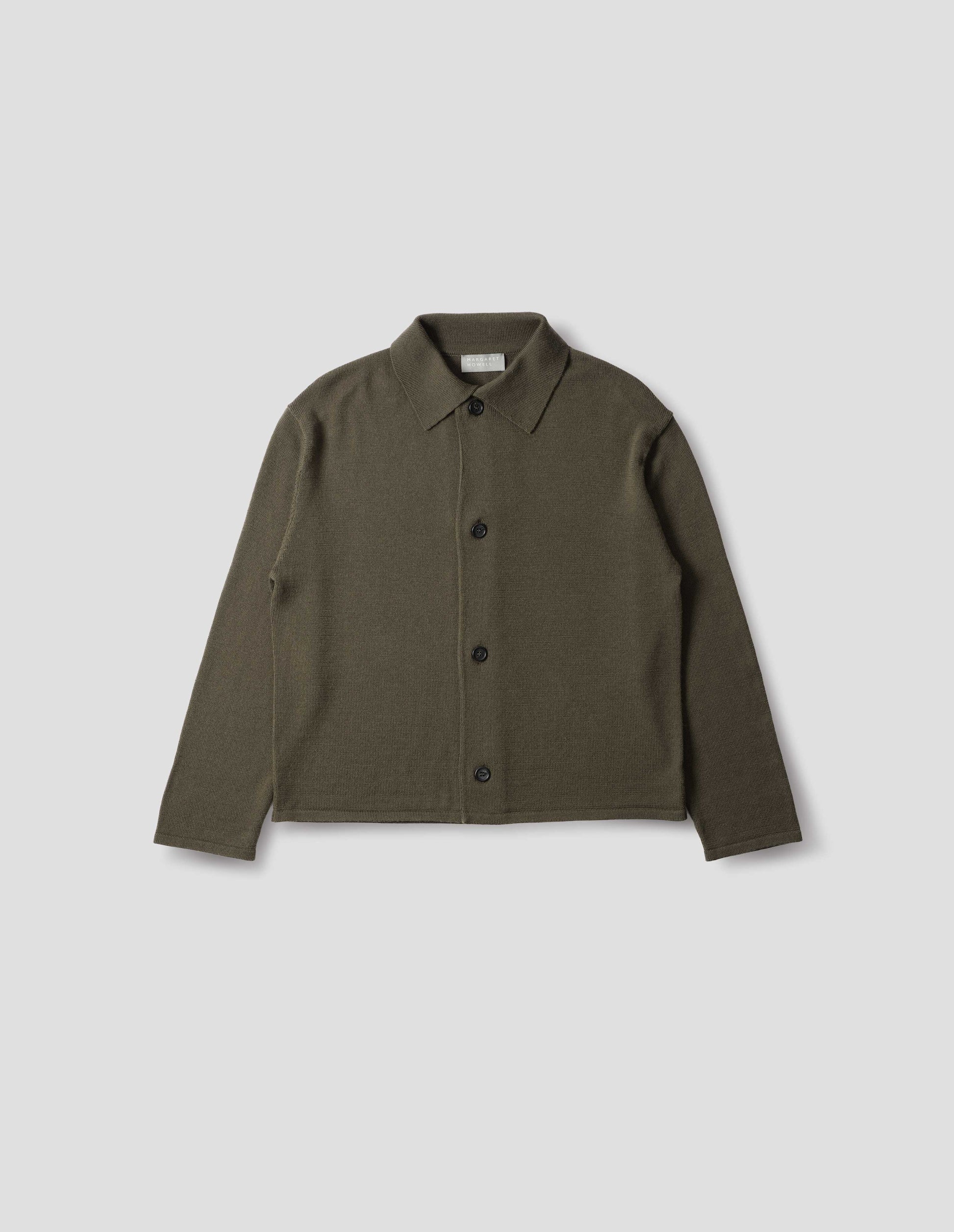 Green merino cardigan with jersey stitch, fully fashioned collar, horn button fastening, set-in fully fashioned sleeves, and tubular hem and cuffs. Front flat lay view.