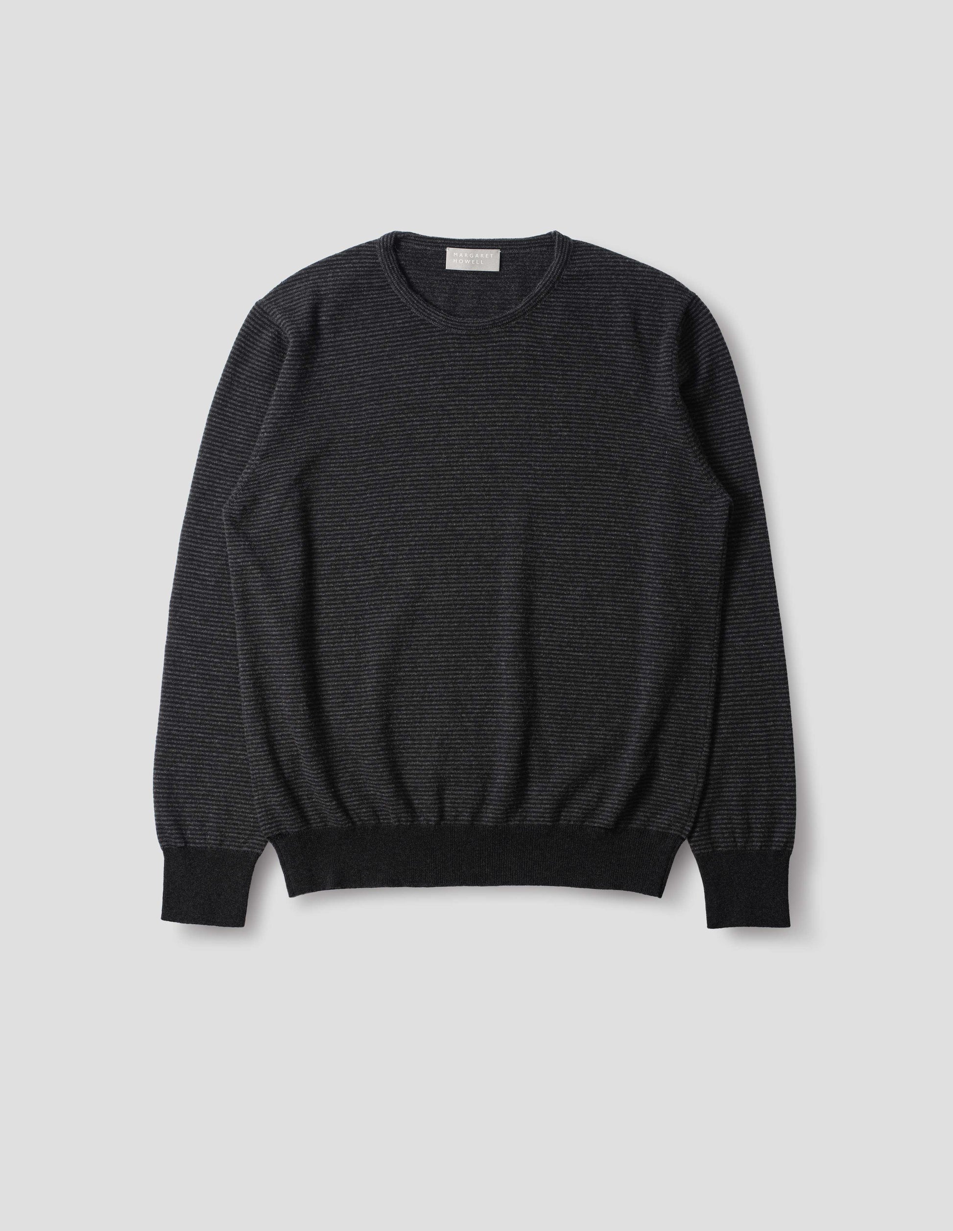 Dark grey merino cashmere jumper with black stripes, crew neck with tubular collar, and with contrast rib on cuffs and hem. Front flat lay view.