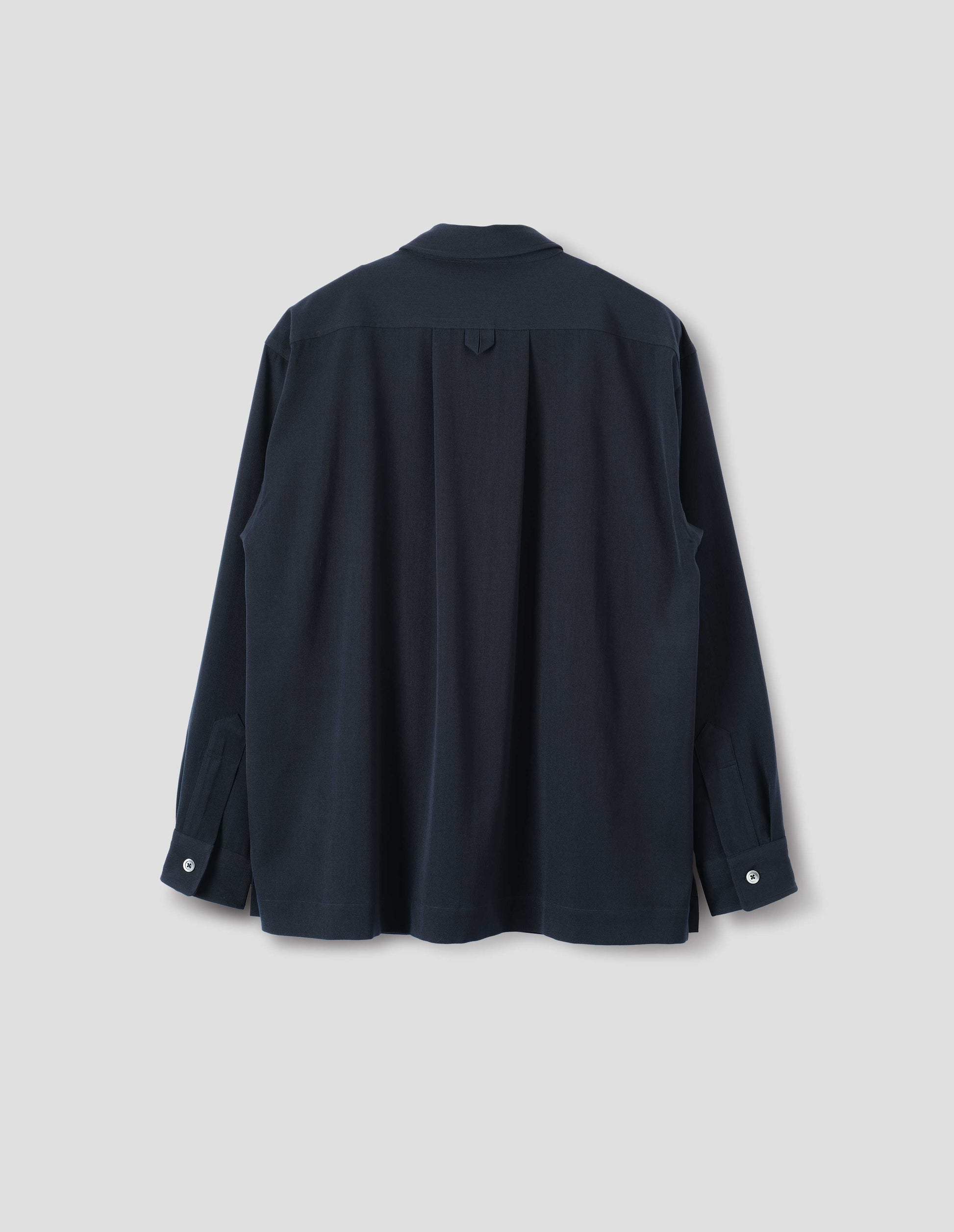 Dark blue wool shirt with mother of pearl buttons on cuffs, wide box pleat and hanger loop detail on back yoke. Back flat lay view.