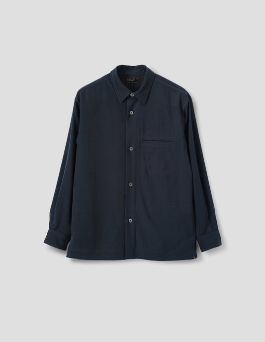 Dark blue wool shirt with mother of pearl buttons and welt chest pocket. Front flat lay view.