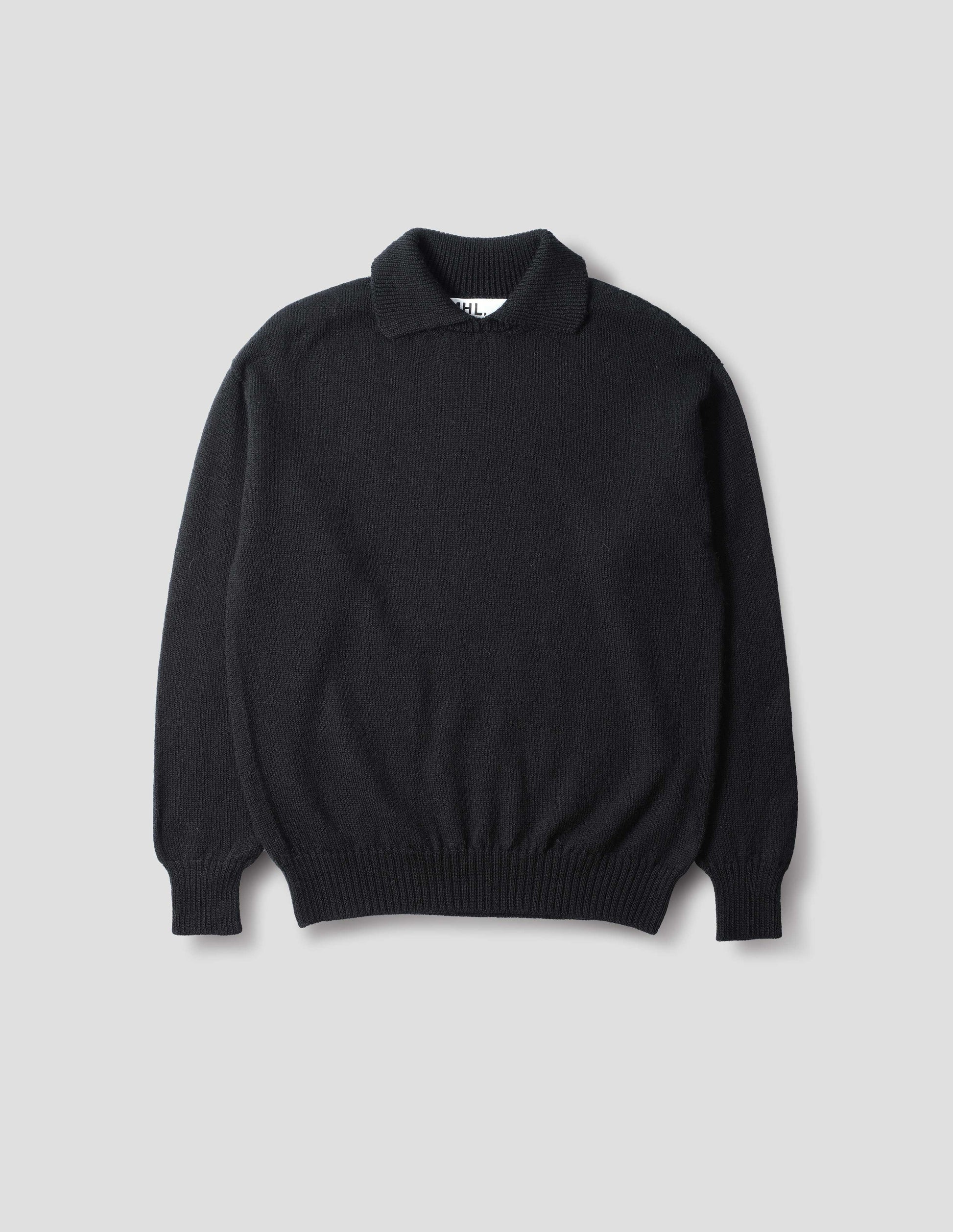 Collared wool sweater in black with a wide rib linked on collar, plain knit body, and deeper ribbed cuffs. Finished with a straight hem, front flat view.