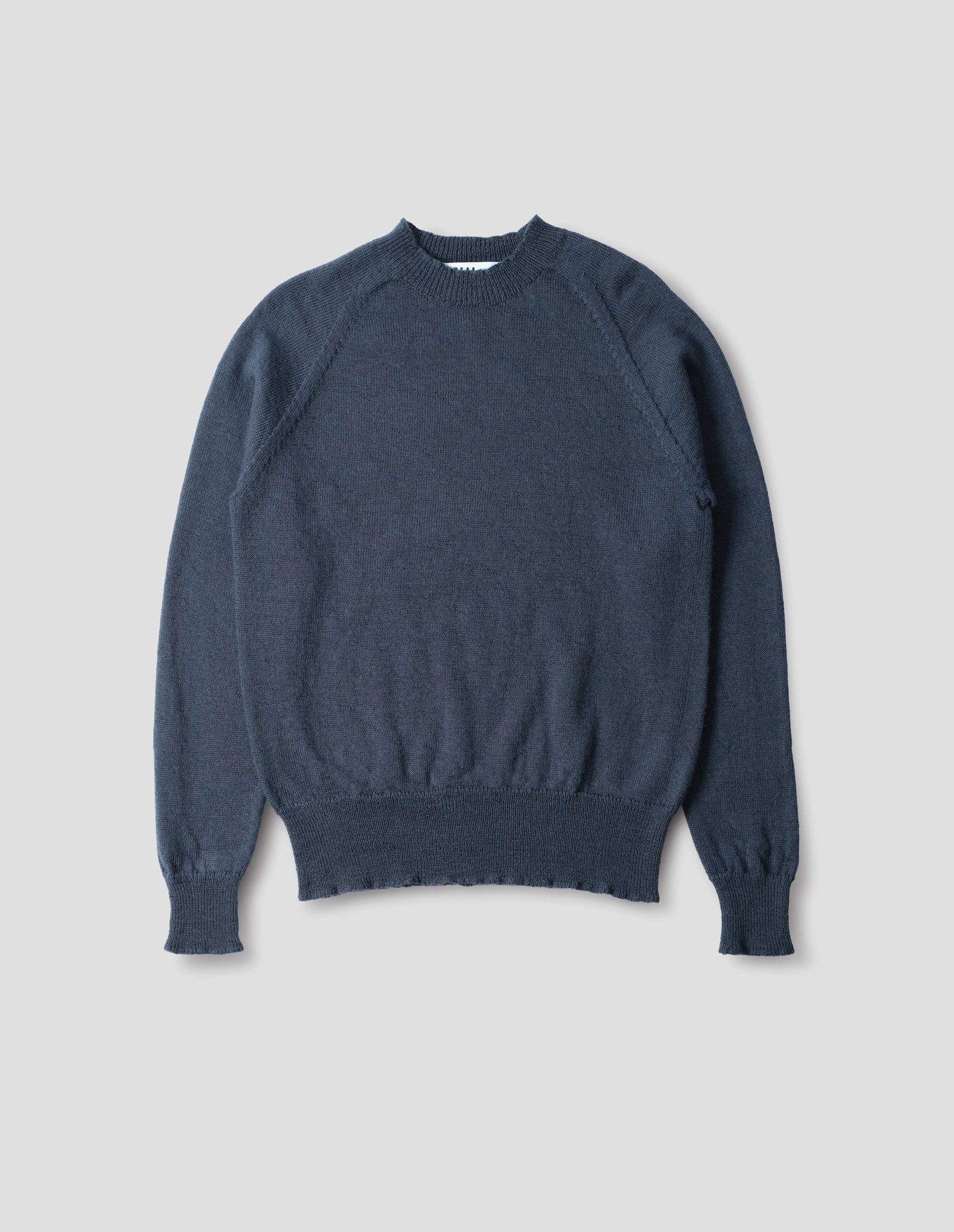 Blue wool jumper, with raglan sleeve, rib collar, cuffs and hem, front flat lay view.