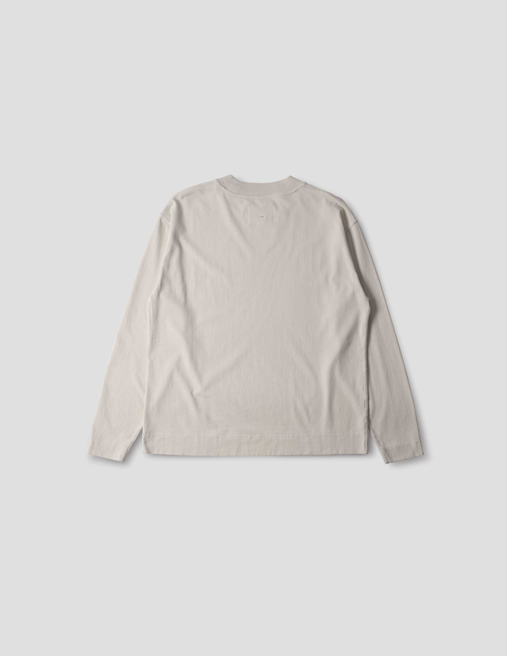 Off white cotton t shirt, with long sleeves, flatlock stitching, a deep ribbed collar and ribbed triangle insert on the shoulder, back flat lay view.
