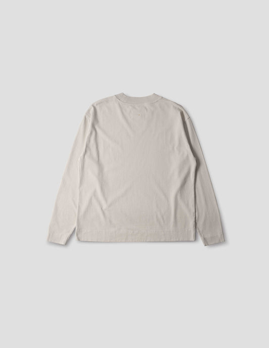 Off white cotton t shirt, with long sleeves, flatlock stitching, a deep ribbed collar and ribbed triangle insert on the shoulder, back flat lay view.