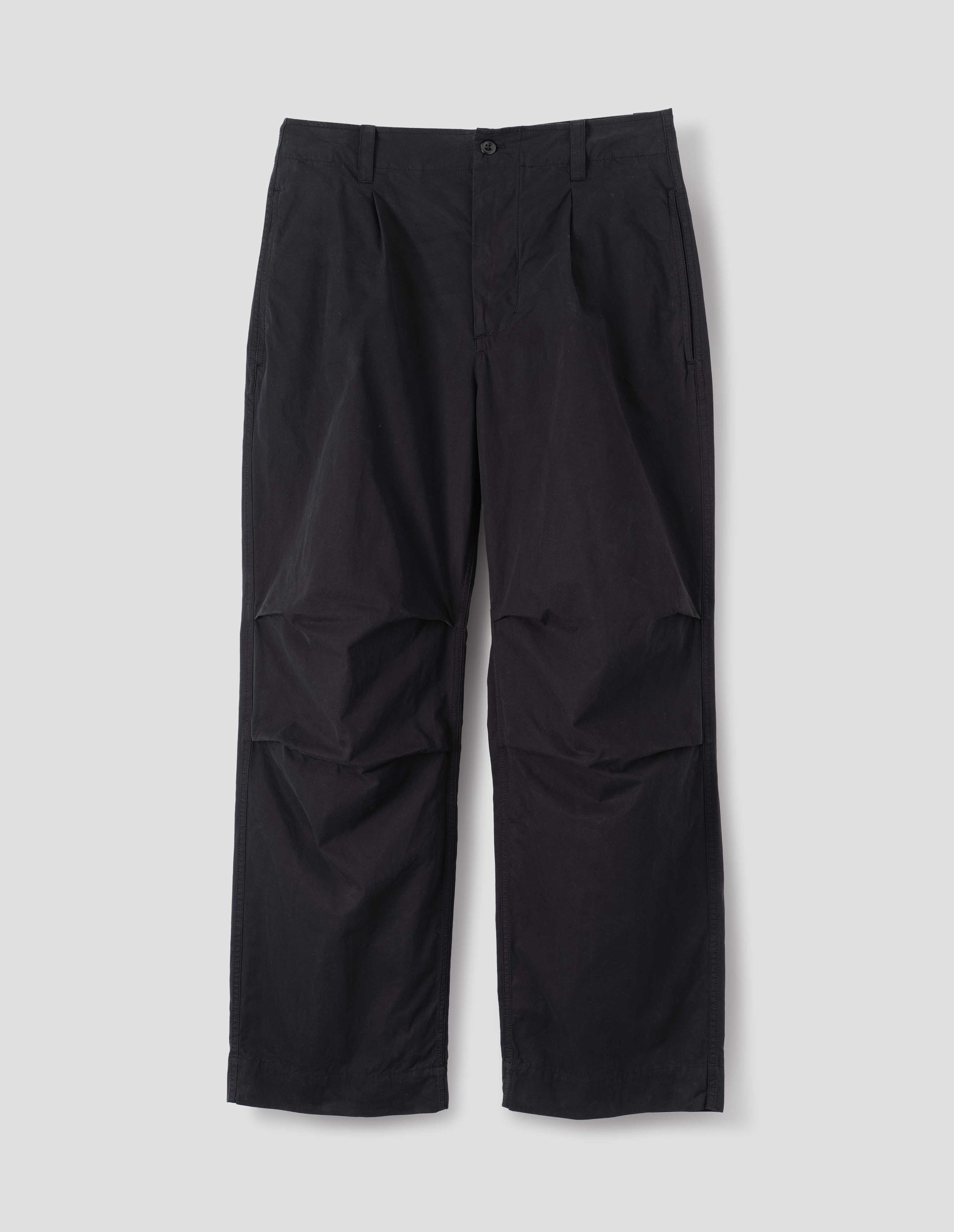Black cotton trousers, with side seam pockets, single pleats and pleated knee detailing, front flat lay view.