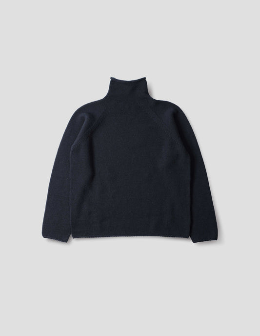 Dark blue high neck wool sweater with raglan sleeves, rolled cuffs and hem, back flat lay view.