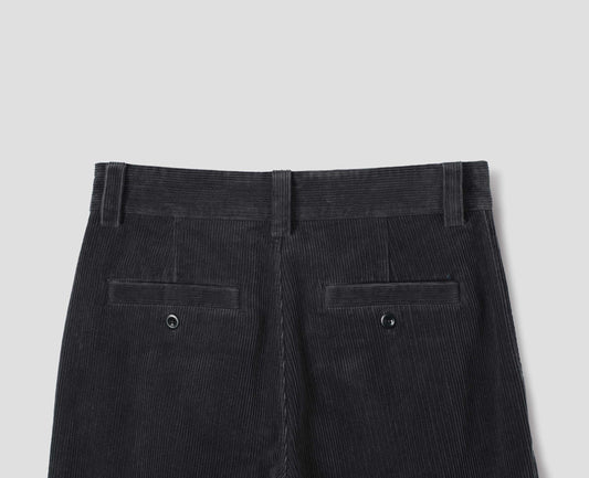 Dark grey cotton corduroy trousers with belt loops and two welt back button fastening pockets. Back flat lay view.