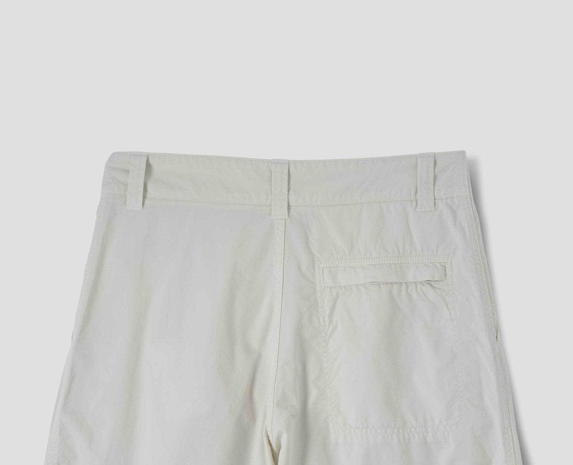 Off white cotton trousers, finished with one stitch-through back pocket with a concealed Vislon zip fastening, back flat lay view.