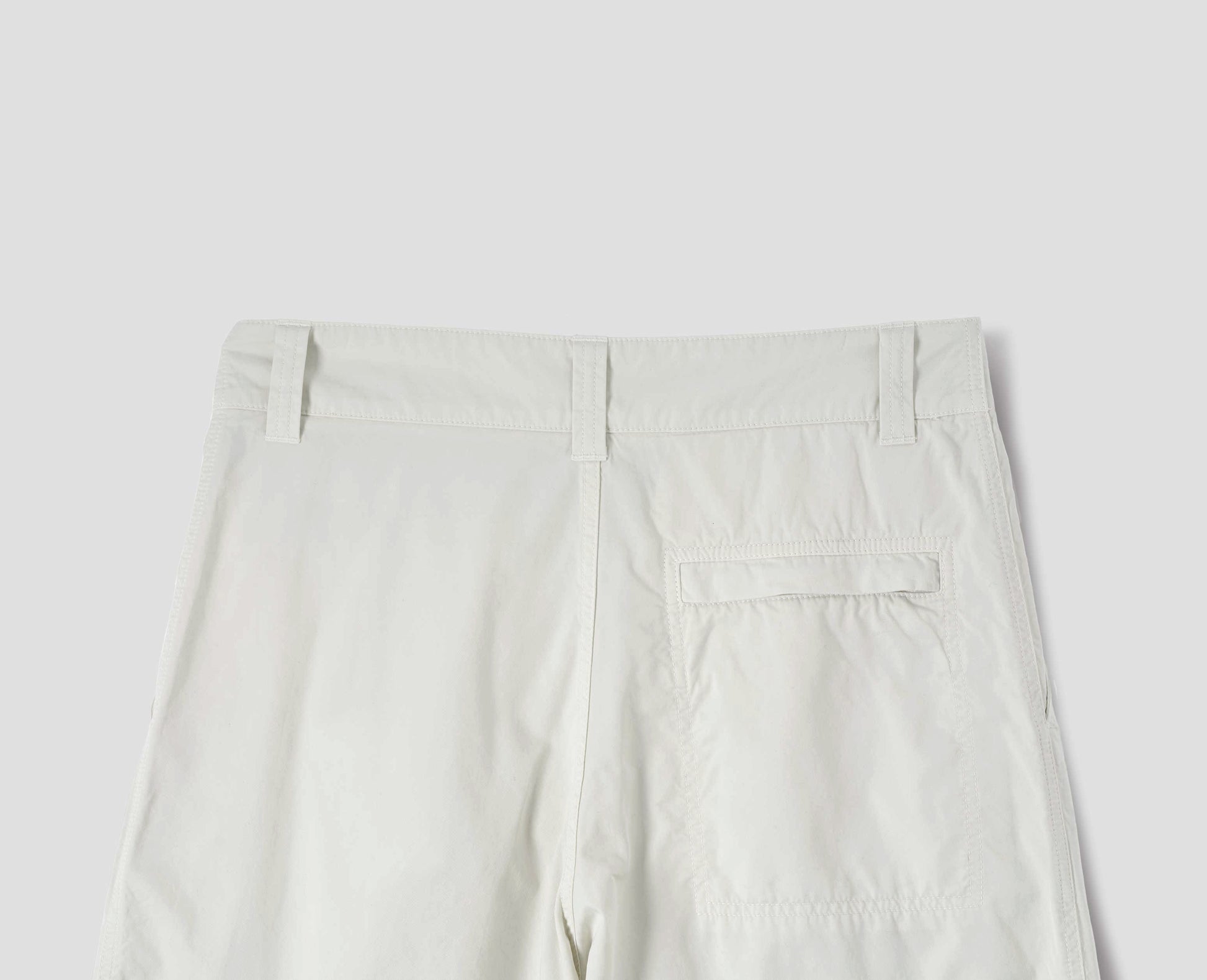 Off white cotton trousers, finished with one stitch-through back pocket with a concealed Vislon zip fastening, back flat lay view.