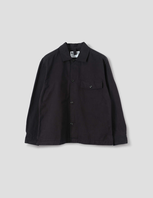 Black cotton overshirt, with a grown-on, button-fastening placket, spread collar, and welt chest pockets with flaps and button closure, finished with shirt cuffs. Front flat lay view. 