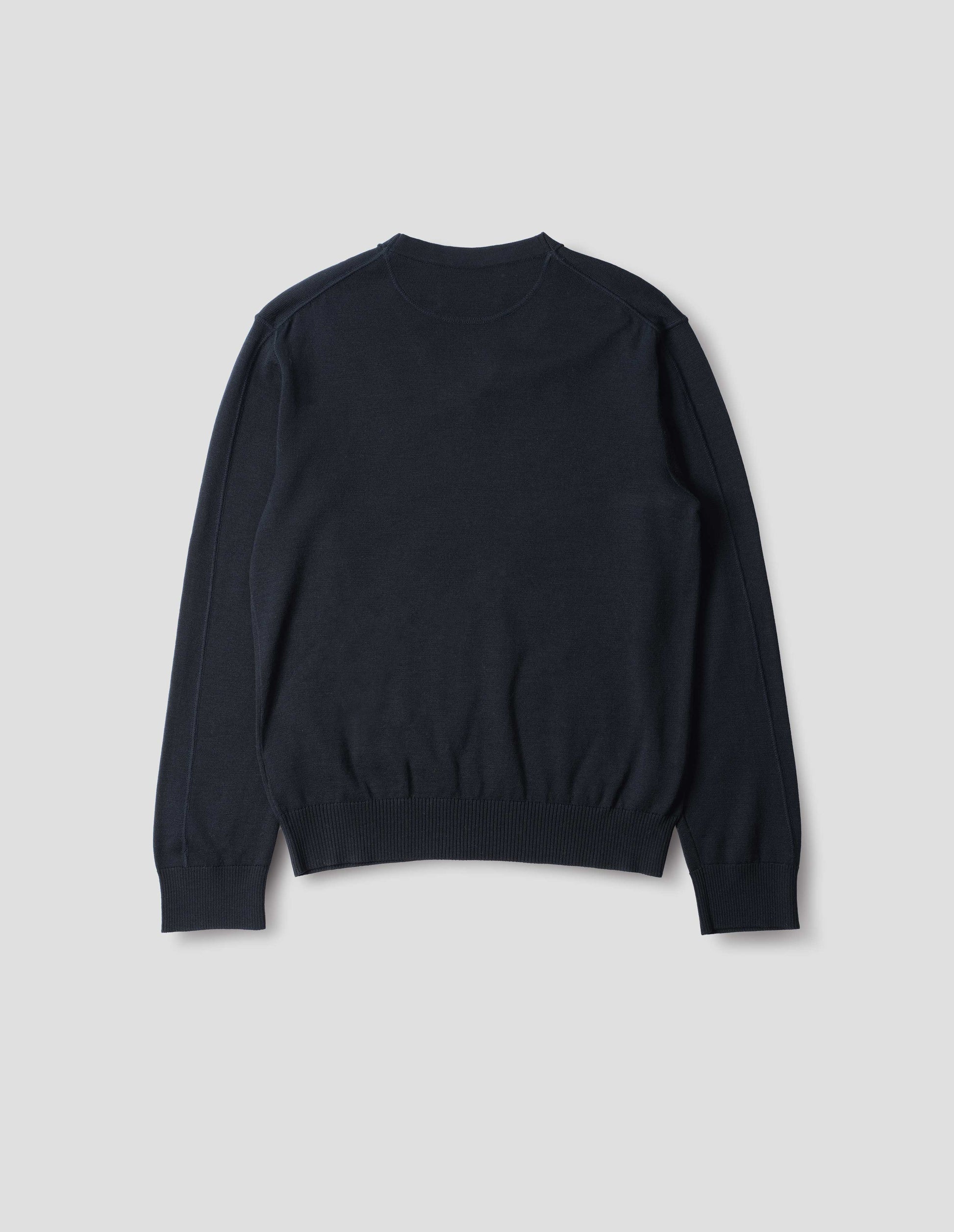 Dark navy fine wool jumper, with a half-moon yoke at the back neck, flatlock detailing on the sleeves with rib cuffs and hem, back flat lay view.