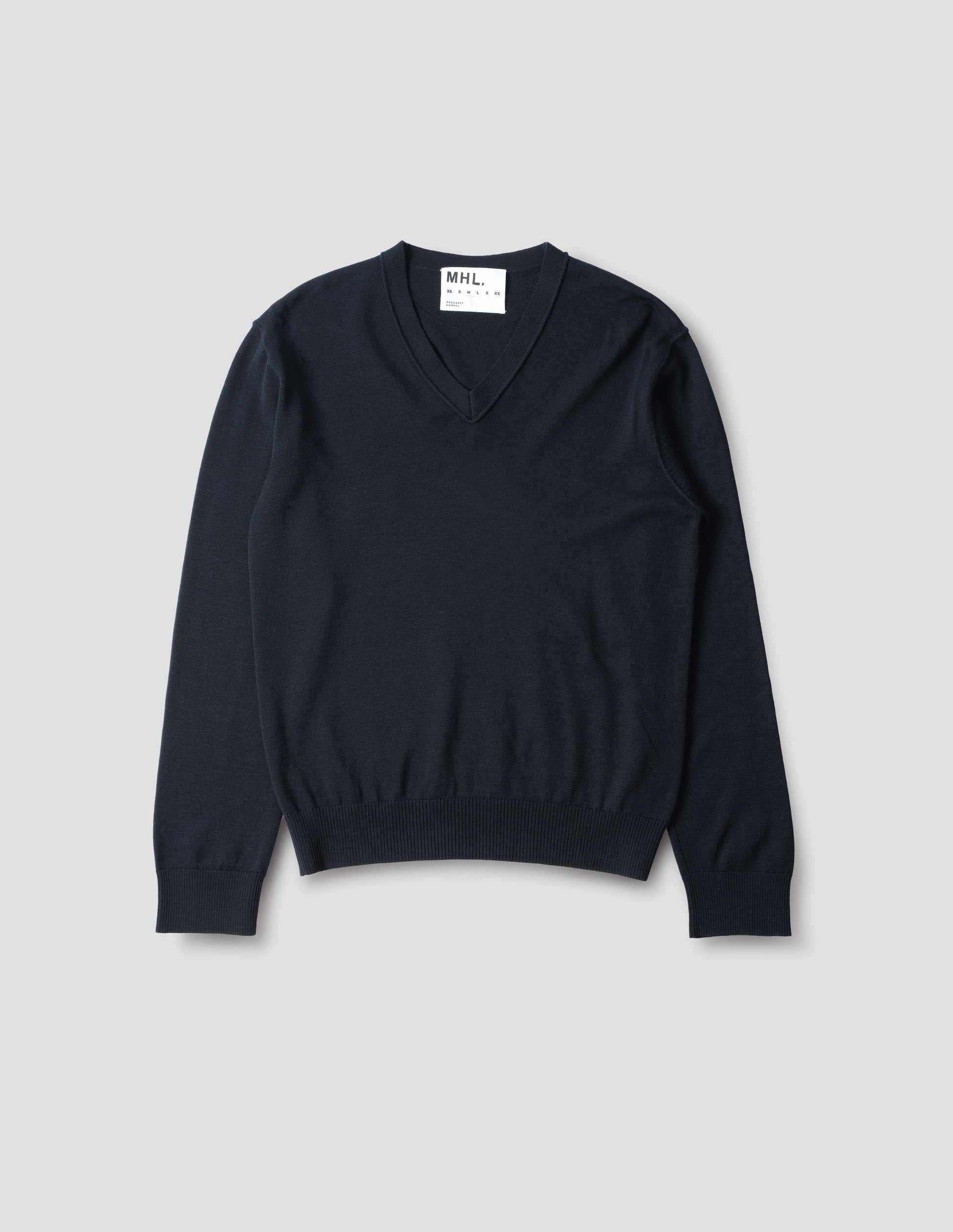Dark navy fine wool jumper with v neck, flatlock detailing on the sleeves, and laid-on neck trim, cast-off edge details at the neckline with rib cuffs and hem, front flat lay view.